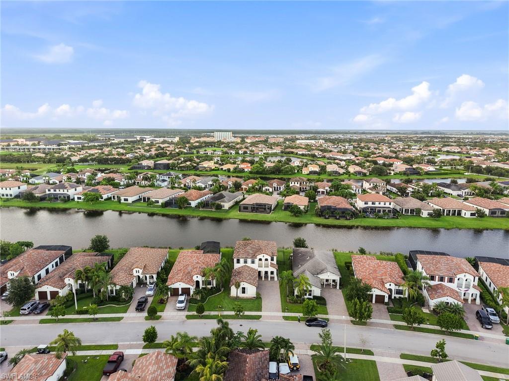Waterfront community featuring homes with red-tile roofs, private driveways, and manicured landscaping