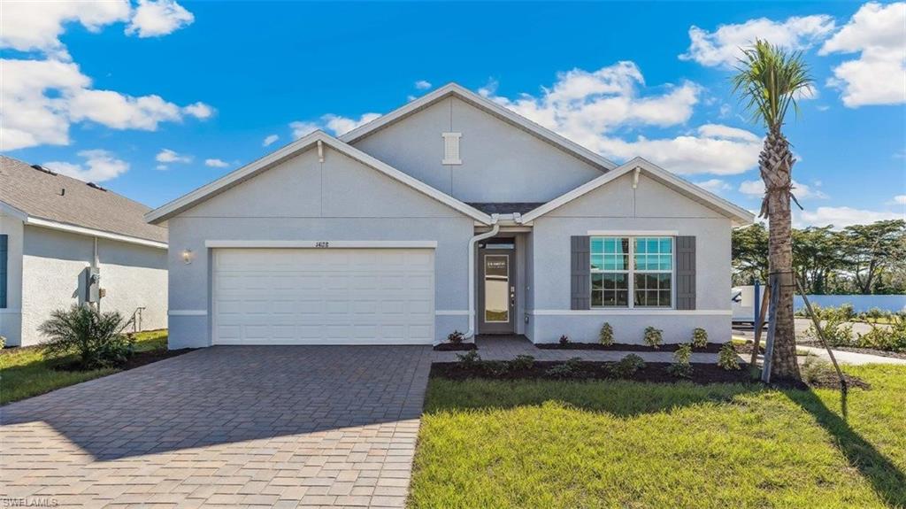 Model Home. Contemporary single-story residence featuring a light gray exterior, an integrated garage with a white door, and a paver driveway