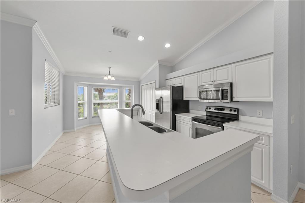 Kitchen featuring a large central island with double sink, white cabinetry, stainless steel appliances, and tile flooring