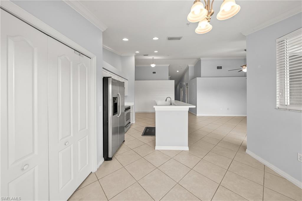 Open concept living area featuring diagonal tile flooring, a kitchen island with sink, stainless steel appliances, and ceiling-mounted light fixtures