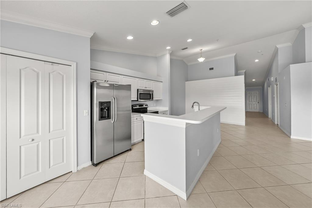 Kitchen with white cabinetry, stainless steel appliances, and a breakfast bar island featuring a single-basin sink