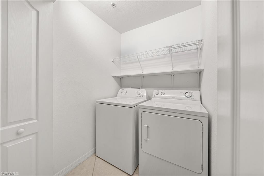 Dedicated laundry space featuring a white washer and dryer, tile flooring, and integrated wire shelving for storage