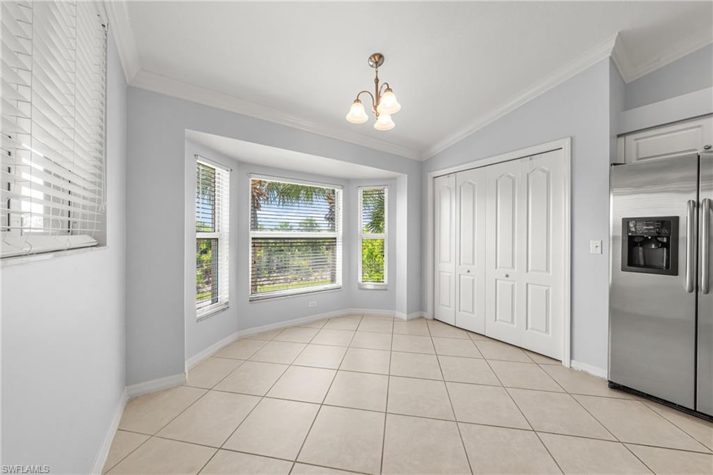 Dining area featuring a bay window, crown molding, white bi-fold closet doors, stainless steel refrigerator, and tiled flooring