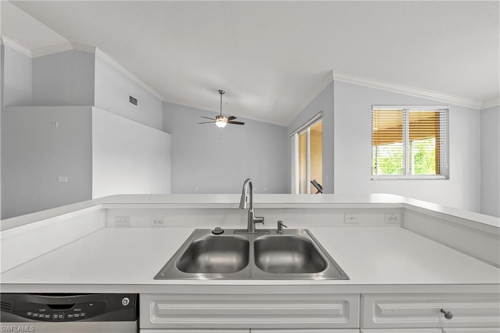 Kitchen counter featuring an undermount double-basin stainless steel sink with a gooseneck faucet, integrated dishwasher, and white cabinetry