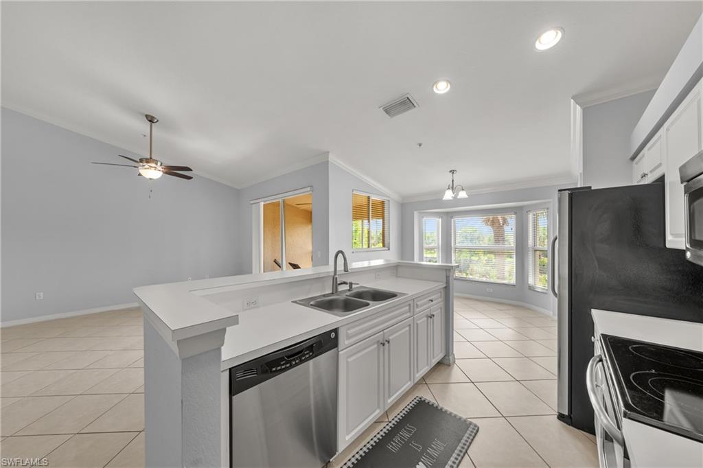 Kitchen island featuring a double-basin sink, stainless steel dishwasher, and white cabinetry