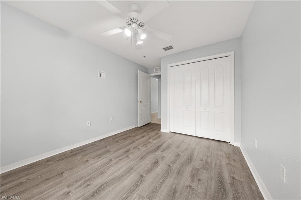Spacious room featuring wood-finish flooring, light gray wall paint, and white trim