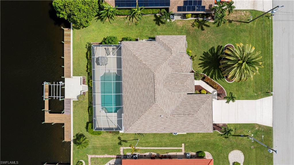 Waterfront property featuring a screened-in swimming pool, private boat dock with lift, and concrete driveway