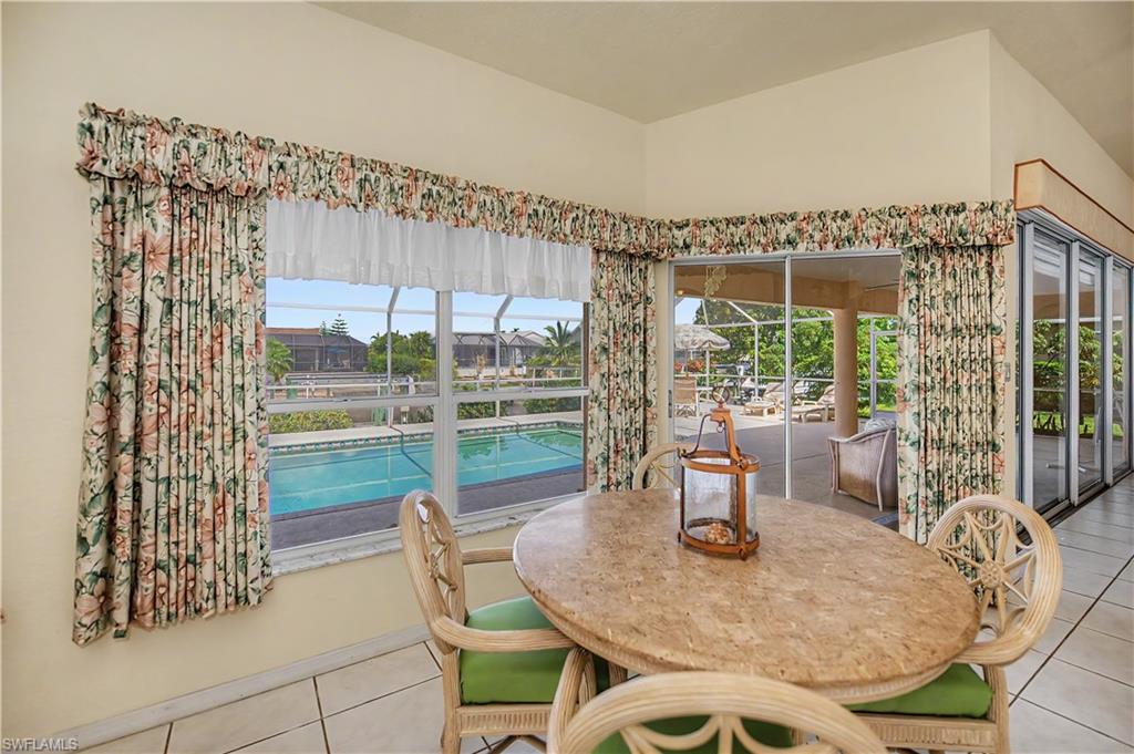 Dining area featuring a tiled floor and a large window overlooking a swimming pool
