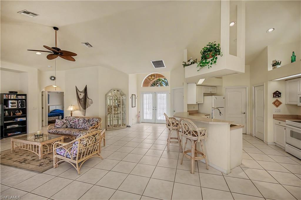 Spacious living area featuring tile flooring, vaulted ceilings, and a ceiling fan