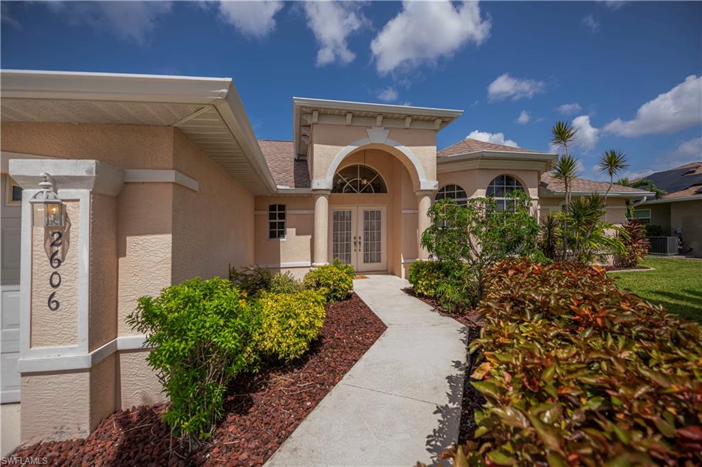 Stucco exterior with arched entry, double front doors, and a bay window