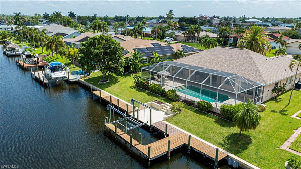 Waterfront property featuring a screened-in swimming pool, private boat dock, and lush green lawn