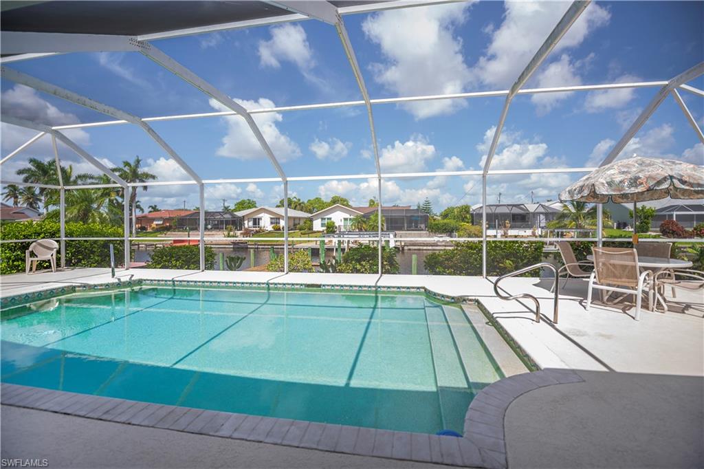 Screened-in pool deck featuring a clear blue swimming pool, concrete patio, and direct water frontage