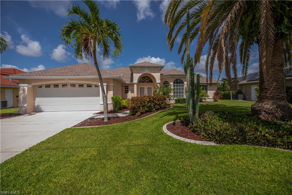 Single-story residence featuring a two-car garage, arched entryways, and a tiled roof