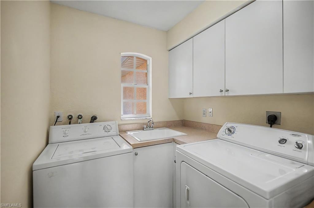 Dedicated laundry area featuring a utility sink, countertop space, and upper cabinetry