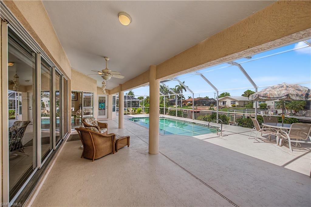 Expansive screened lanai featuring a swimming pool, concrete patio, multiple ceiling fans, and large sliding glass doors