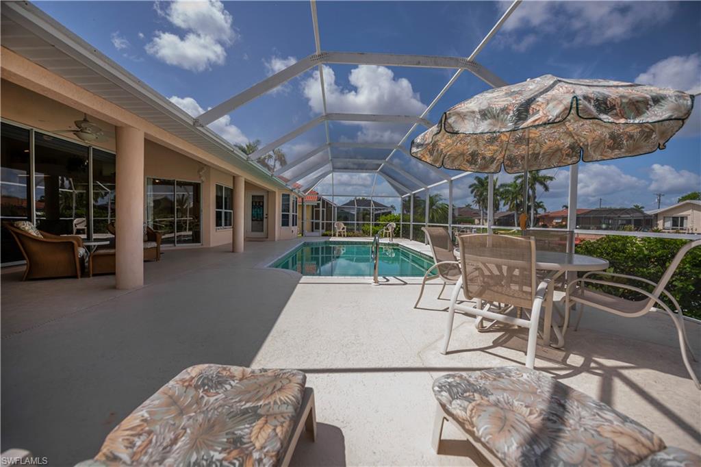 Screened-in outdoor living space with an in-ground swimming pool, expansive concrete patio, and direct access to interior rooms via multiple glass doors