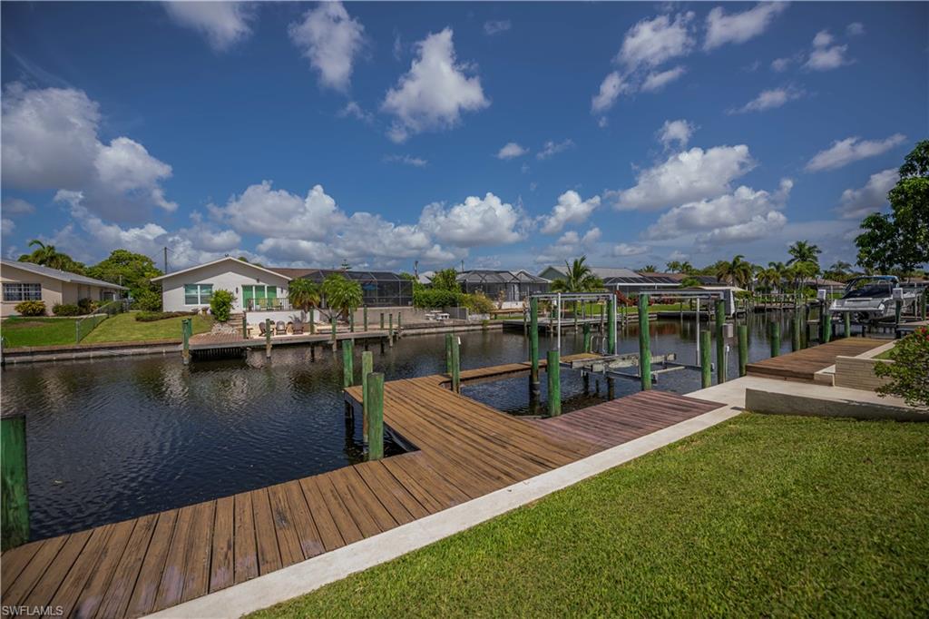 Waterfront property featuring a wood-finish dock, concrete seawall, and boat lift