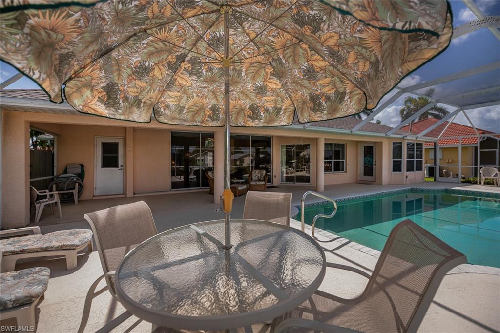 Screened-in pool deck featuring a clear blue swimming pool with a handrail, a concrete patio, and a covered lanai
