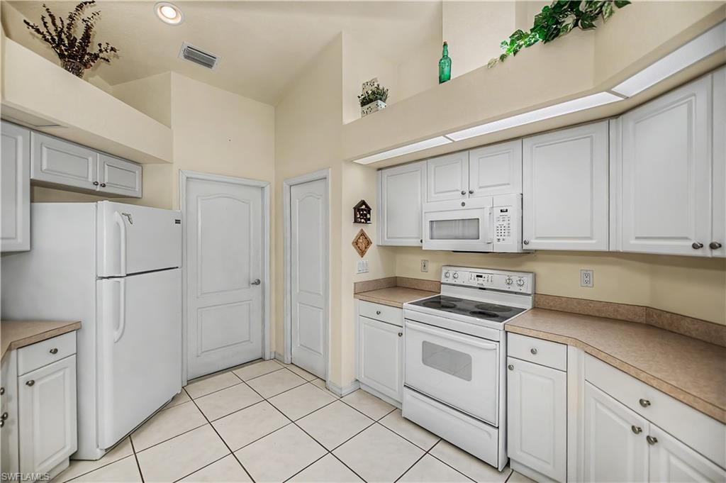 Kitchen featuring white cabinetry, white appliances, recessed lighting, tile flooring, and beige countertops