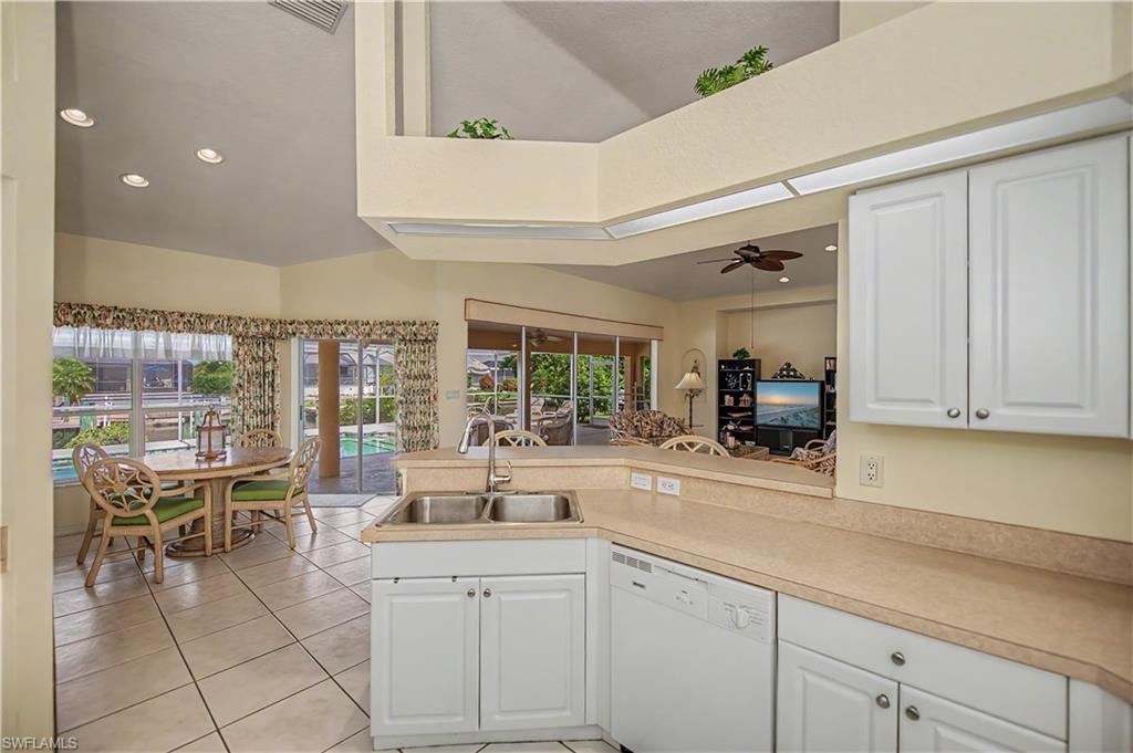 Kitchen featuring white cabinetry, light-toned countertops, and a double-basin stainless steel sink