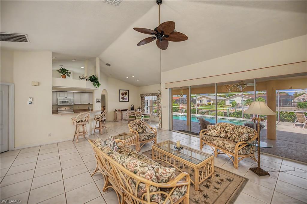 Spacious living area featuring tile flooring, vaulted ceilings, and a ceiling fan