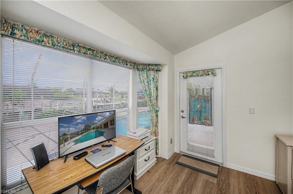 Interior space featuring wood-finish flooring, vaulted ceiling, and an exterior door with decorative glass inserts