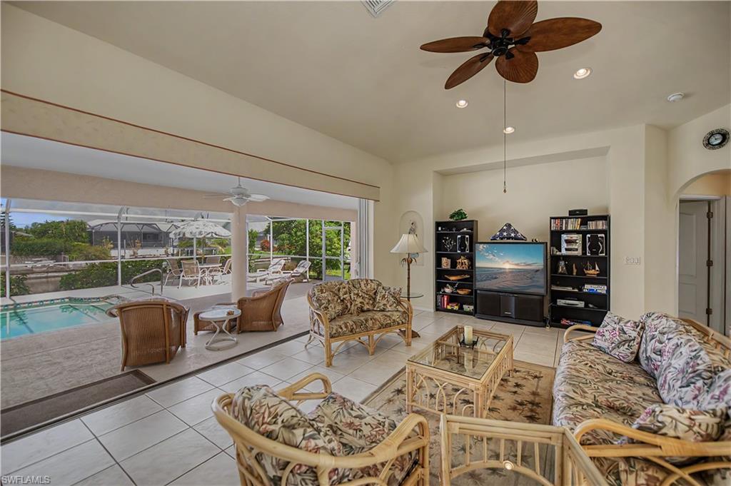 Bright open-concept living area featuring large format tile flooring and a ceiling fan with recessed lighting