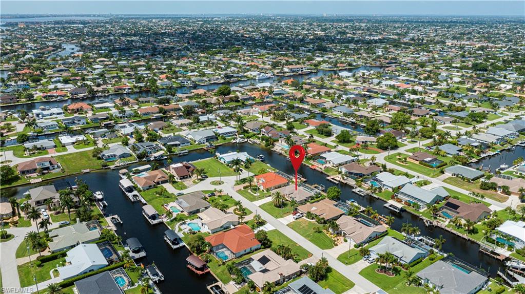 Aerial perspective showcasing a canal-front property with a red tile roof, surrounded by a network of waterways and residential homes
