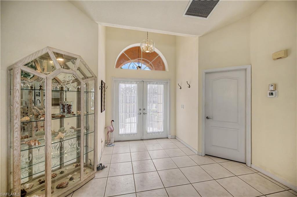 Entry foyer featuring neutral tile flooring, double entry doors with an arched transom, a vaulted ceiling, and a paneled interior door