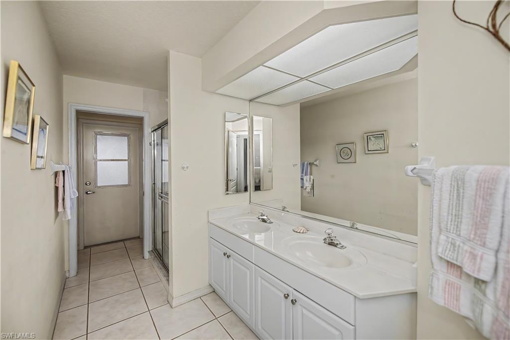 Bathroom featuring a dual-sink vanity with white cabinetry, a large wall-mounted mirror, and tile flooring