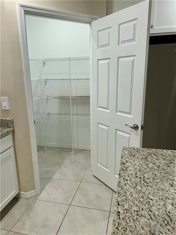Spacious walk-in closet featuring wire shelving, multiple storage levels, and tile flooring