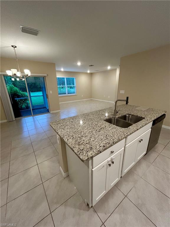 Kitchen island with granite countertop, double basin sink, and white cabinetry