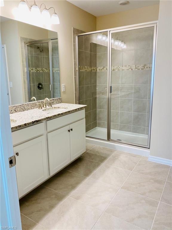 Spacious bathroom featuring a dual vanity with a granite-style countertop, white cabinetry, and brushed nickel fixtures