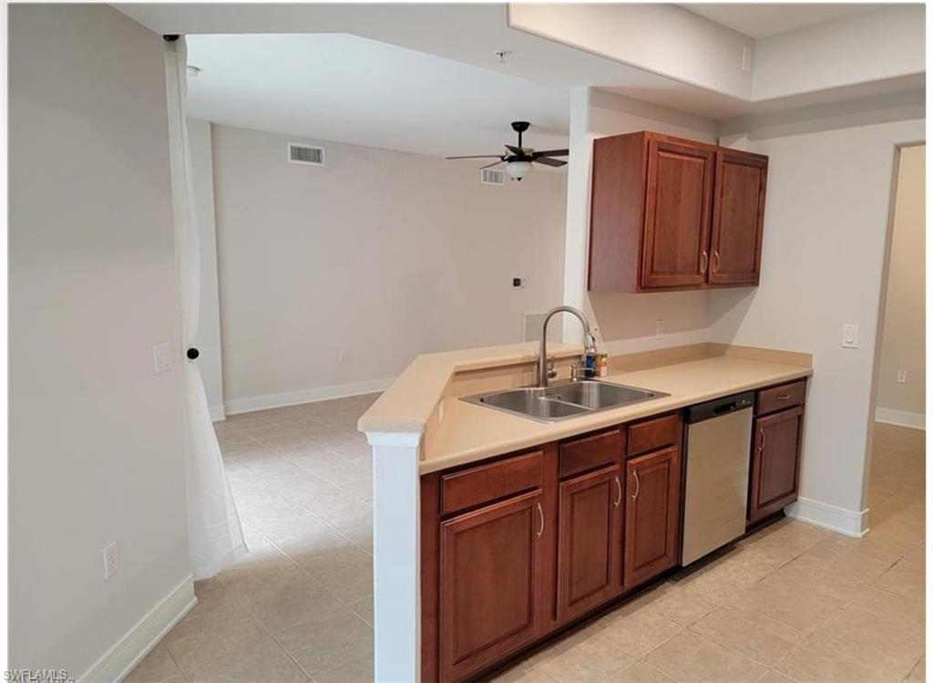 Kitchen featuring light tile patterned floors, stainless steel dishwasher, kitchen peninsula, sink, and ceiling fan
