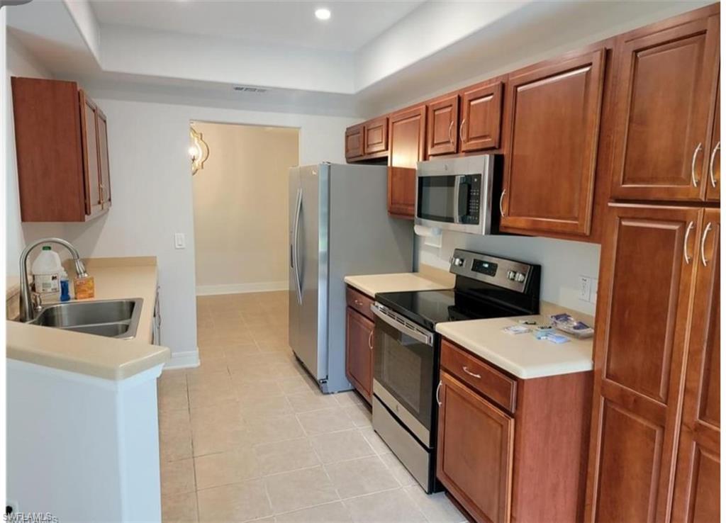 Kitchen featuring a tray ceiling, stainless steel appliances, and sink