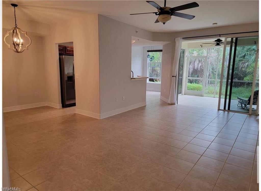 Tiled empty room with ceiling fan with notable chandelier