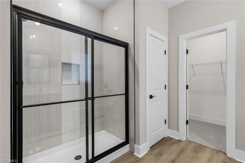 Bathroom featuring light wood-style flooring, a walk in closet, and a stall shower