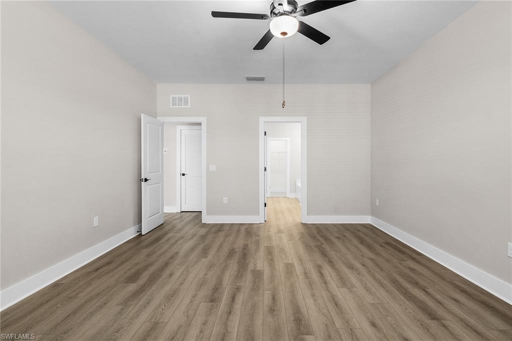 Unfurnished bedroom featuring wood finished floors, a ceiling fan, and ensuite bathroom