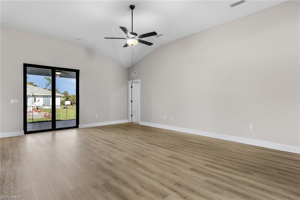 Empty room with light wood finished floors, vaulted ceiling, and ceiling fan