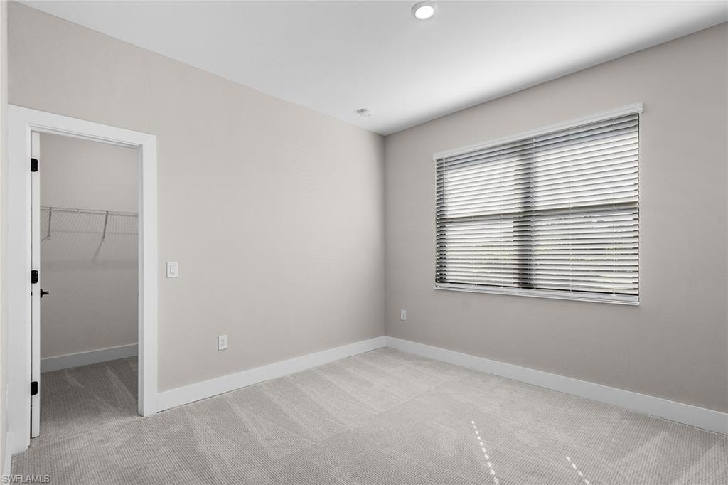 Unfurnished bedroom with light colored carpet and a walk in closet