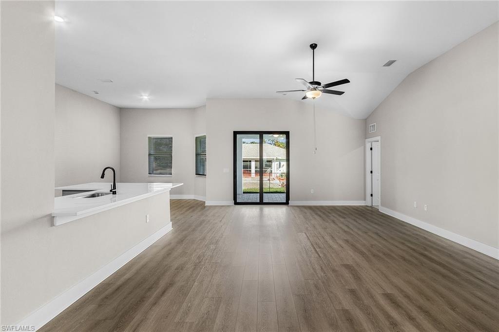Unfurnished living room with light wood finished floors, lofted ceiling, and ceiling fan