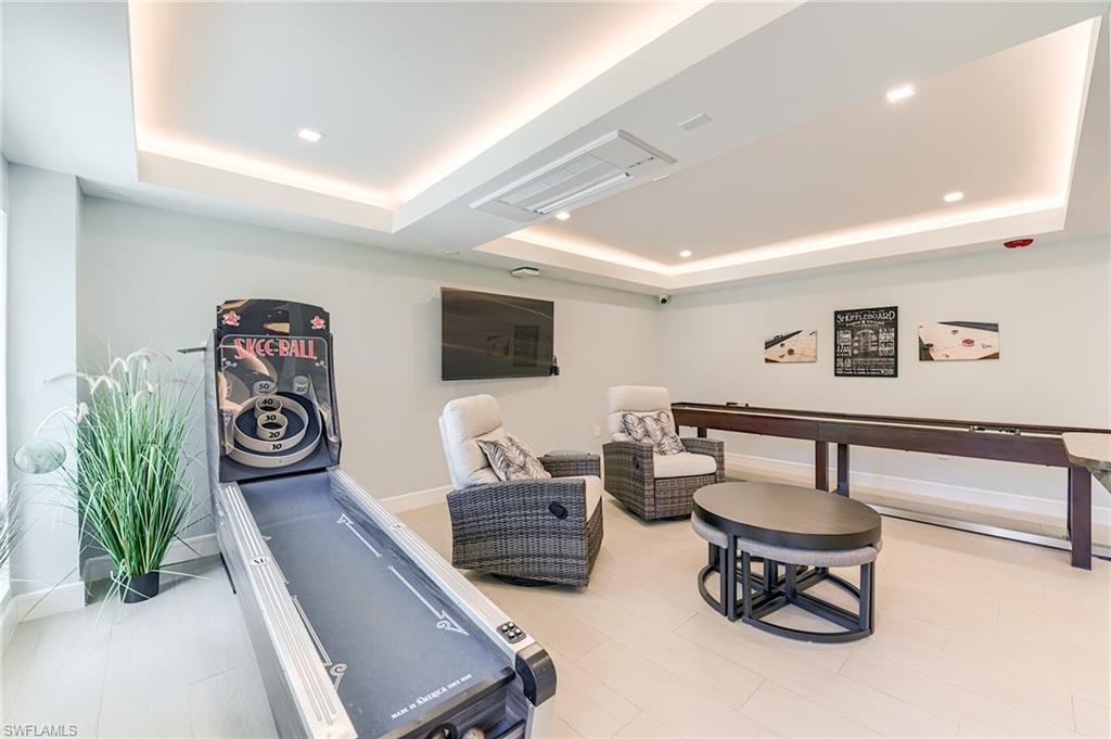 Recessed lighting, tray ceiling, wall-mounted television, shuffleboard table, and light tile flooring