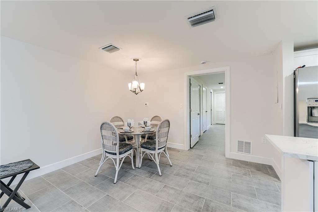 Recessed ceiling lighting, updated ceiling light fixture, tile flooring, white baseboards, and a doorway leading to an interior hallway