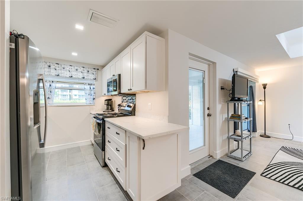 Kitchen featuring white cabinetry, light countertops, stainless steel appliances, and a mosaic tile backsplash