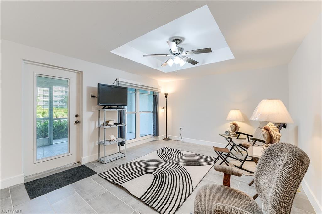 Recessed ceiling with a ceiling fan, light-toned tile flooring, white walls, and a full-light exterior door