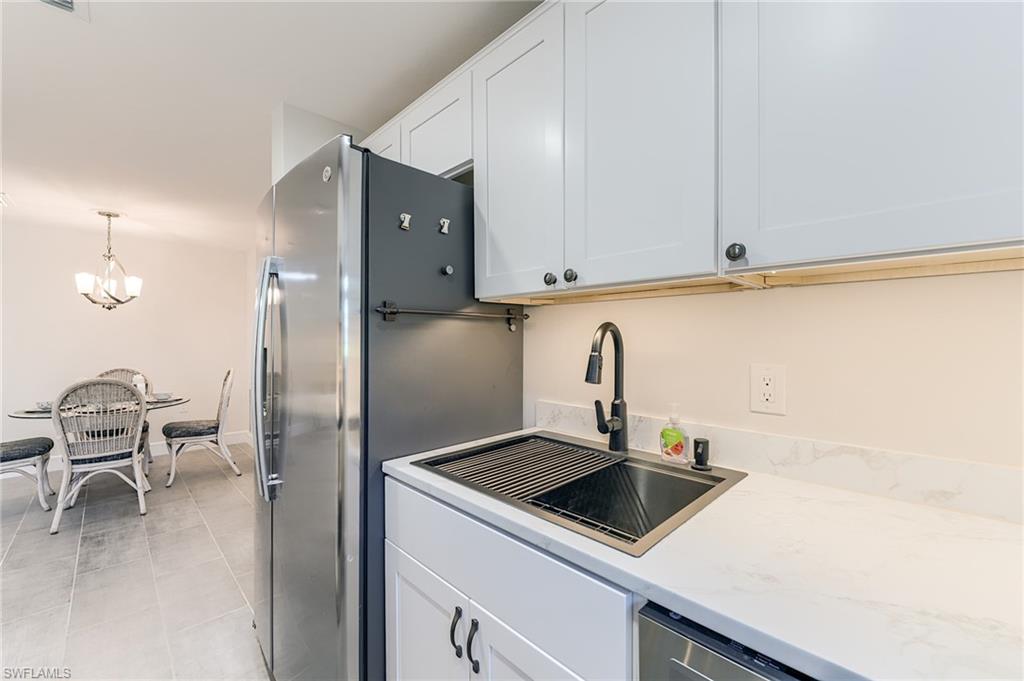 Stainless steel appliances, white shaker-style cabinetry, quartz countertops, undermount sink with a matte black faucet, and tiled flooring