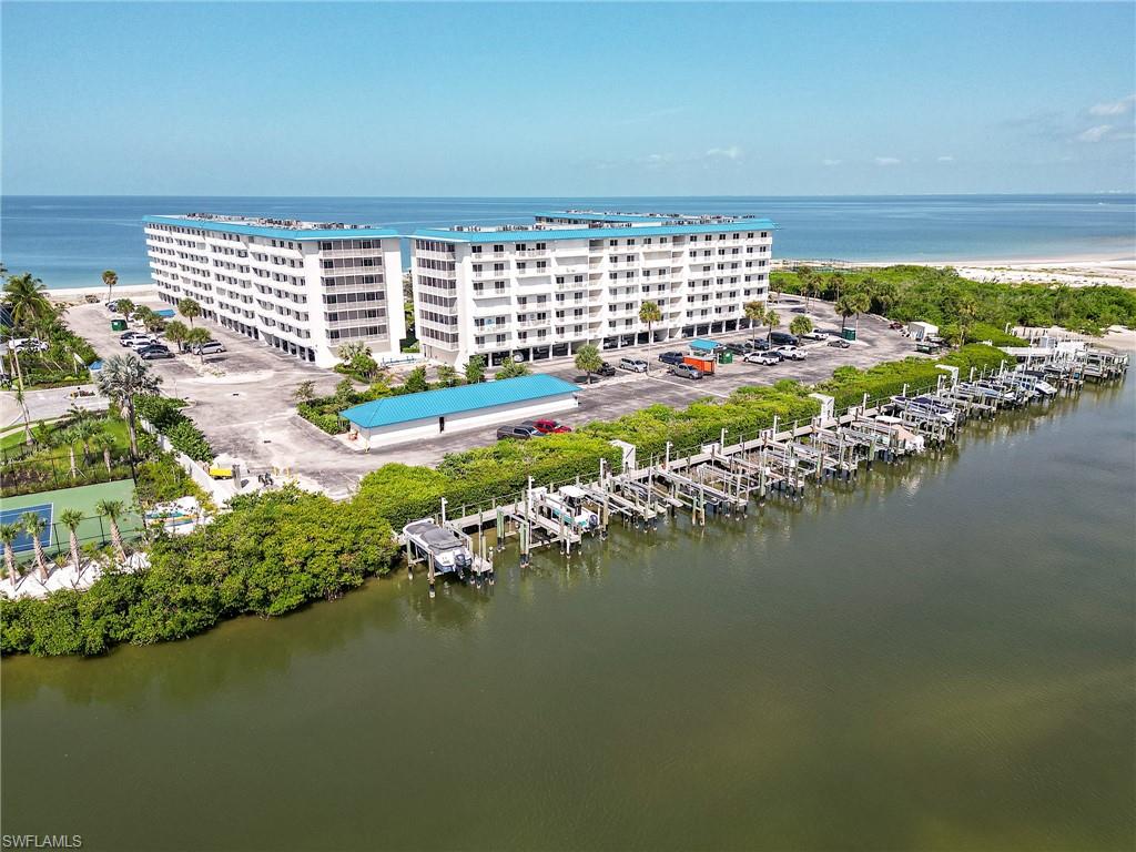 Waterfront condominium complex featuring a multi-slip marina, direct beach access, ample parking, and an outdoor tennis court