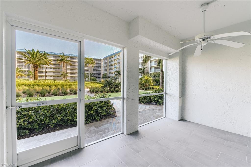 Screened lanai featuring large format tile flooring, a ceiling fan, and a tropical landscape backdrop
