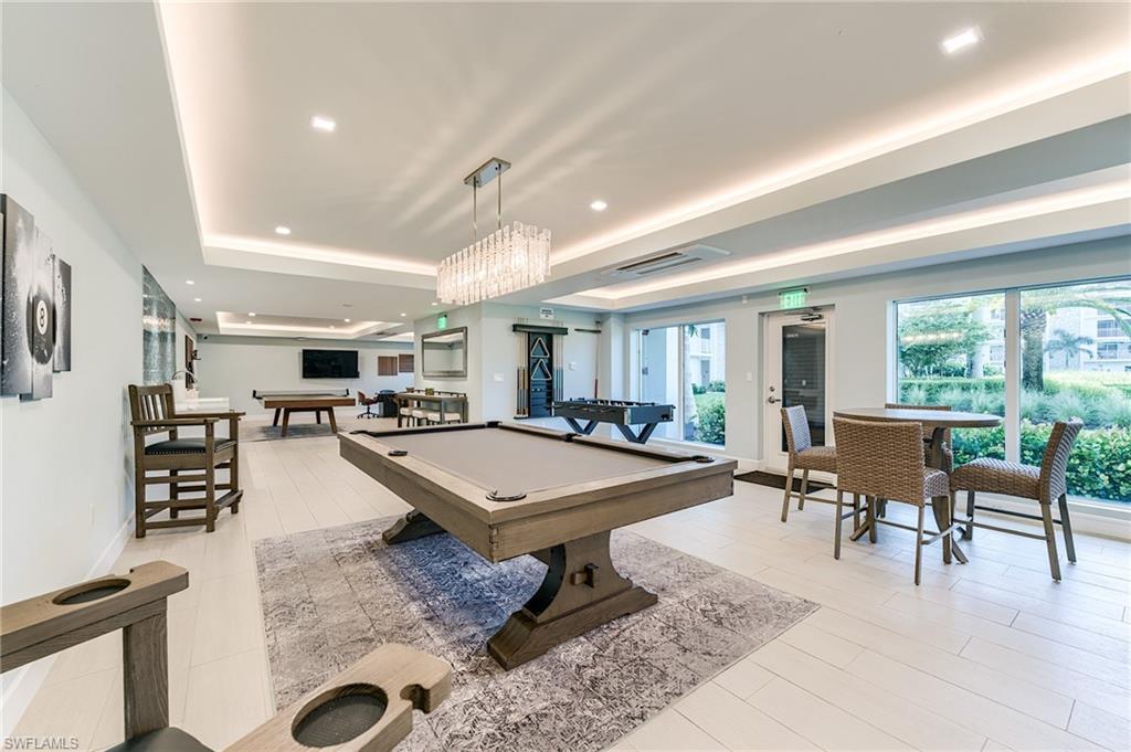 Spacious recreation room with recessed lighting, a decorative chandelier, and large windows