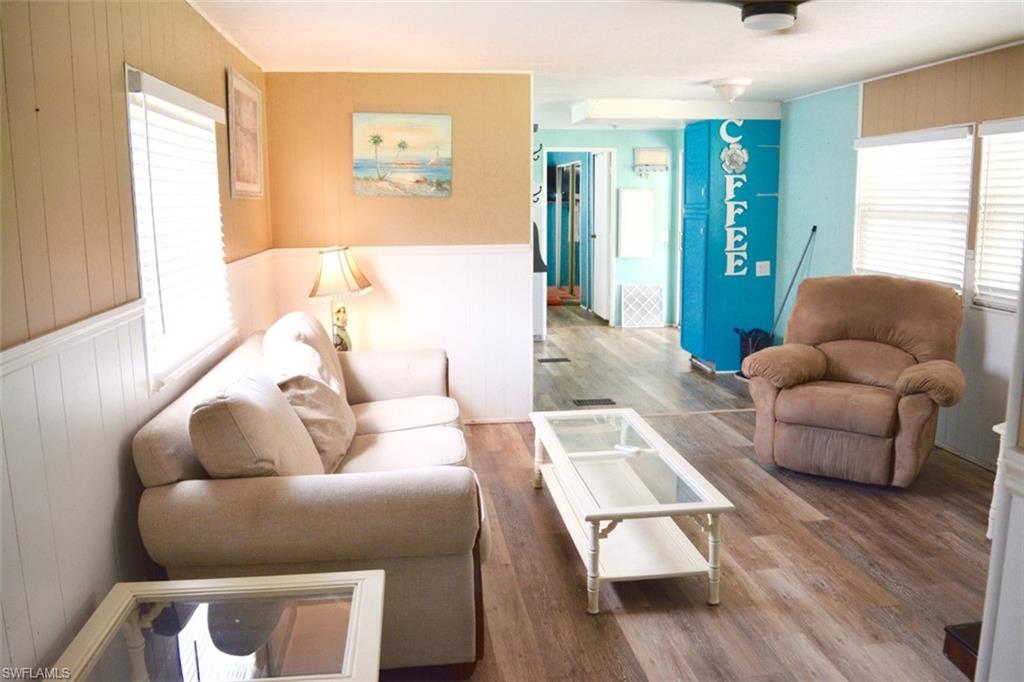 Living area featuring wood-finish flooring, half-wall wainscoting, and multiple windows with blinds